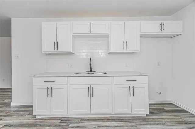 a kitchen with white cabinets and sink