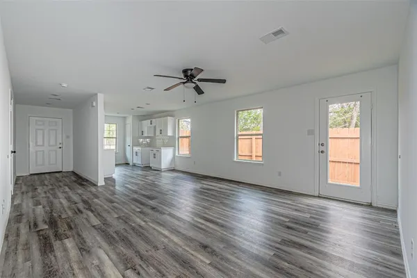 a view of an empty room with wooden floor and a window