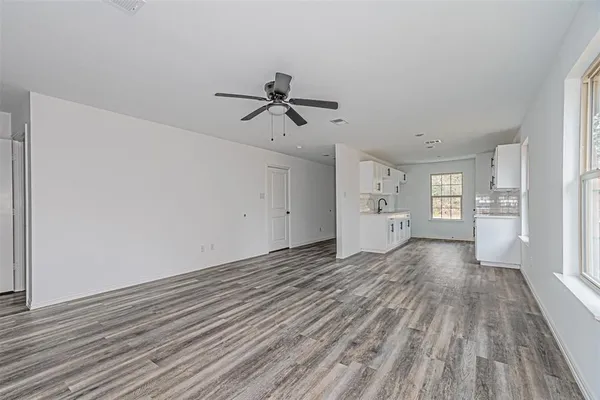 a view of empty room with wooden floor and window