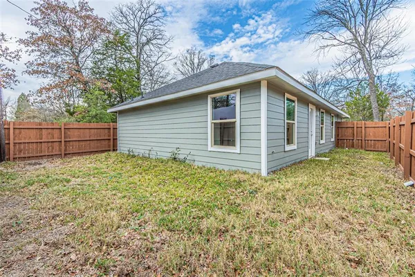 a backyard of a house with wooden fence and large tree
