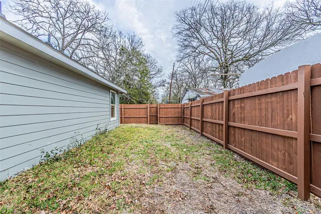 a view of backyard with wooden fence and large trees