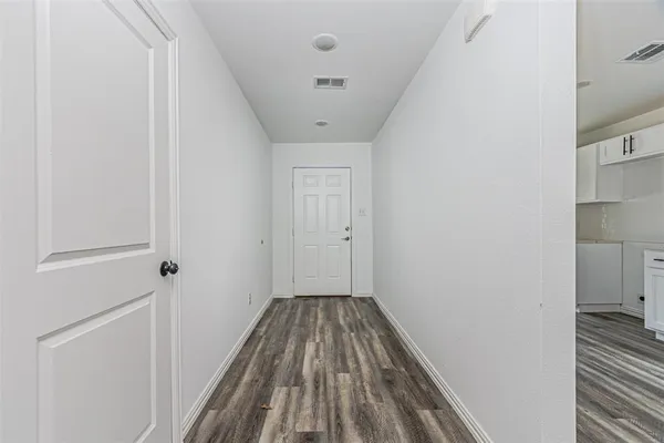 a view of a hallway with wooden floor and a bathroom