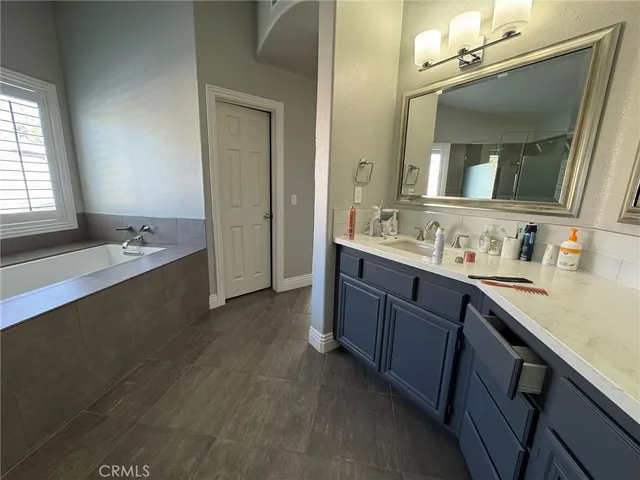 a spacious bathroom with a sink double vanity granite tub shower and a mirror