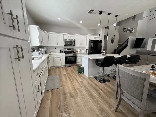 a kitchen with stainless steel appliances a stove a sink a refrigerator cabinets and a dining table