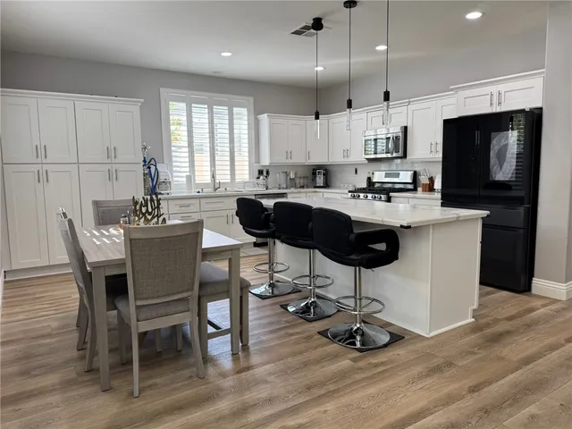 a kitchen with kitchen island a dining table chairs and white cabinets
