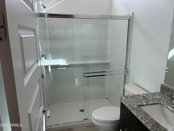 a bathroom with a granite countertop sink and a toilet