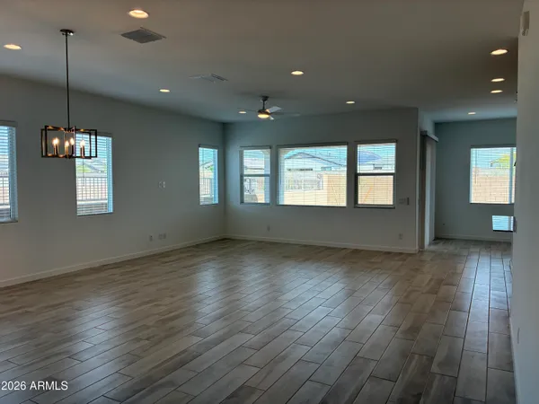 a view of an empty room with wooden floor and fan