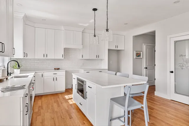 a kitchen with stainless steel appliances granite countertop white cabinets and a window