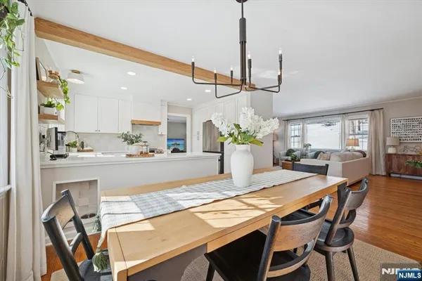 a view of a dining room and livingroom with furniture wooden floor a chandelier