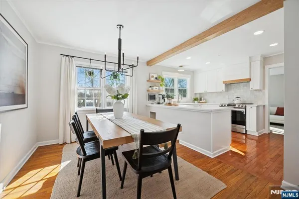 a view of a dining room and livingroom with furniture wooden floor a rug a chandelier