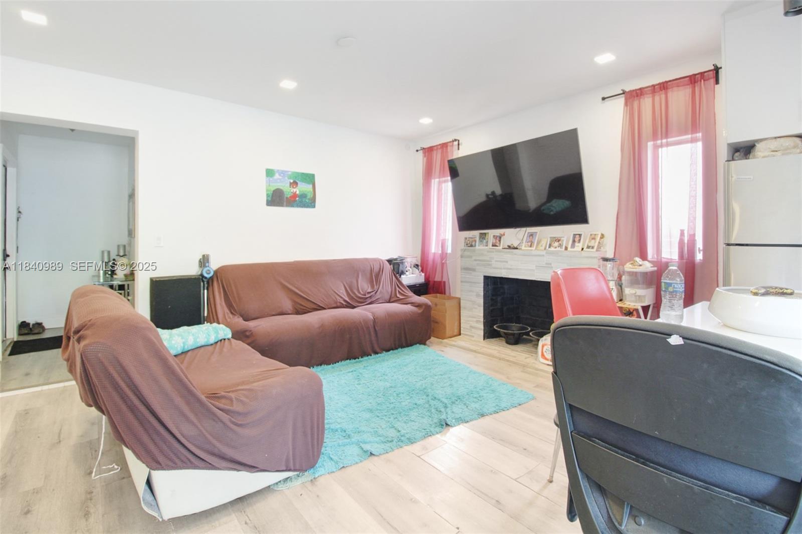 1745 Northwest 49th Street Miami, FL 33142 - Photo 15 of 30 a living room with furniture a flat screen tv and a fireplace
