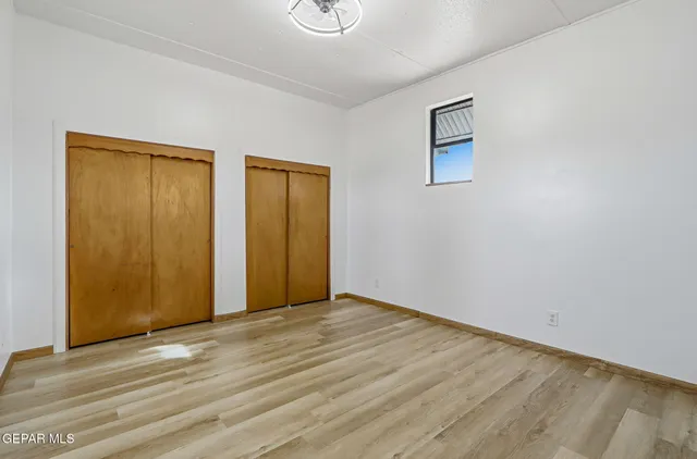 a view of an empty room with wooden floor and closet