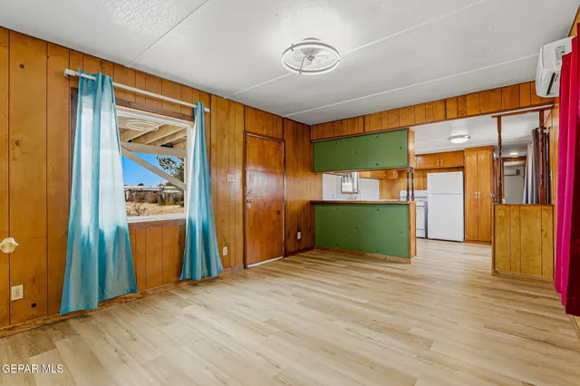a view of a livingroom with wooden floor and a refrigerator