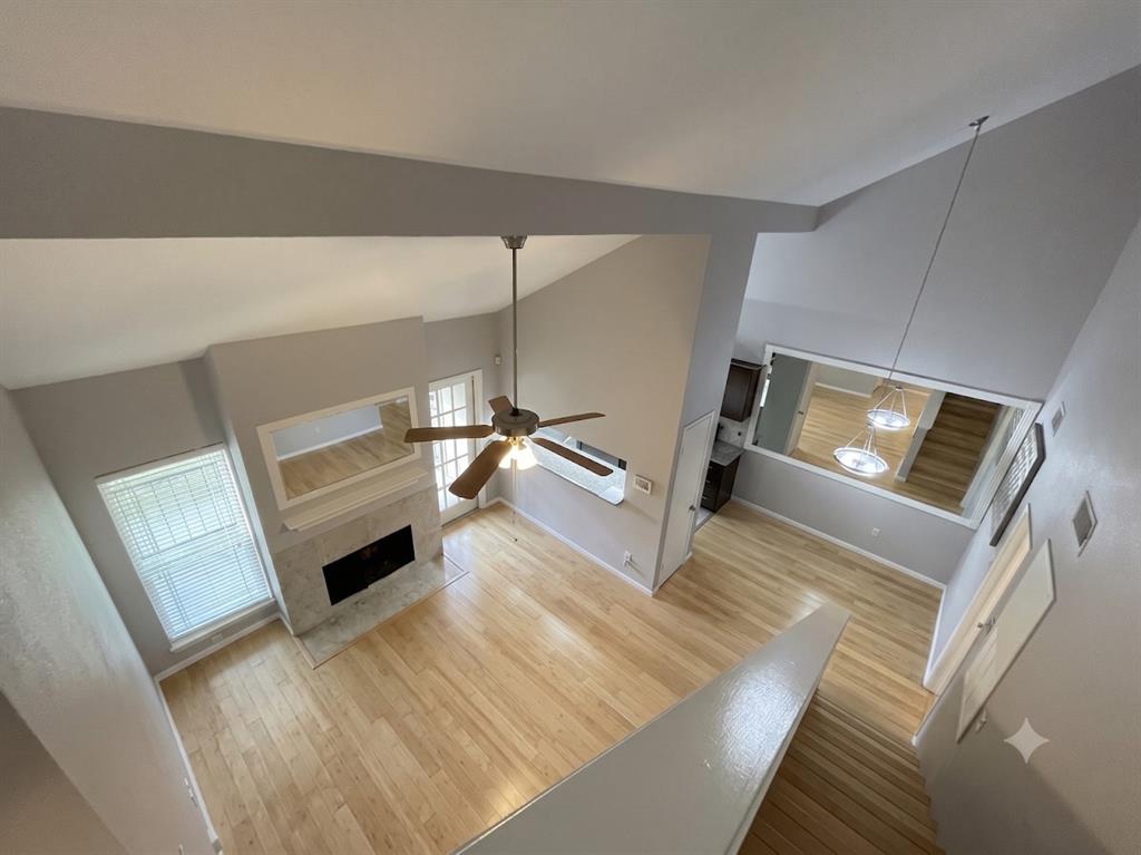 5981 Arapaho Road, Unit 1004 Dallas, TX 75248 - Photo 8 of 16 Vaulted ceilings, wood-finish flooring, fireplace with stone surround, ceiling fan, and staircase with wood treads