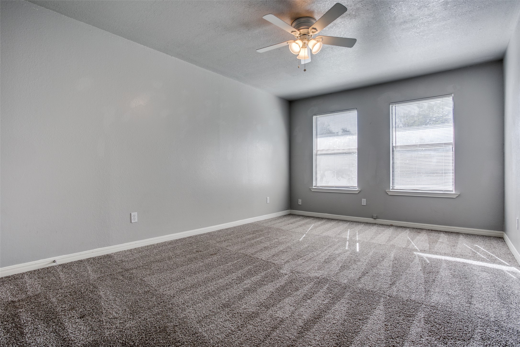106 Verna Spur, Unit B Georgetown, TX 78628 - Photo 19 of 25 A spacious room features plush carpet and multiple sun-filled windows, ideal for tranquil living.