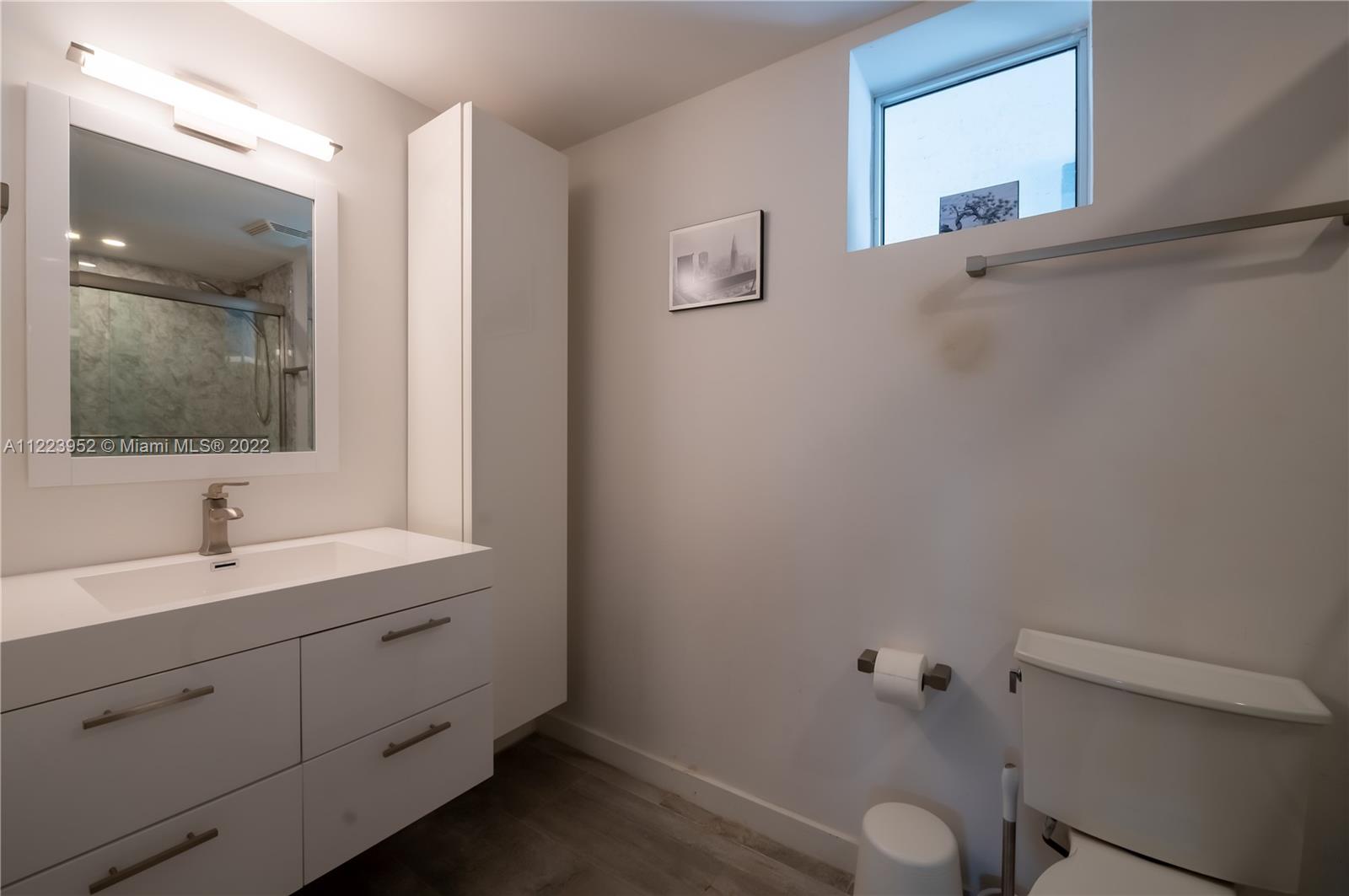 3339 Virginia Street, Unit 339 Miami, FL 33133 - Photo 7 of 13 a bathroom with a sink and mirror with toilet