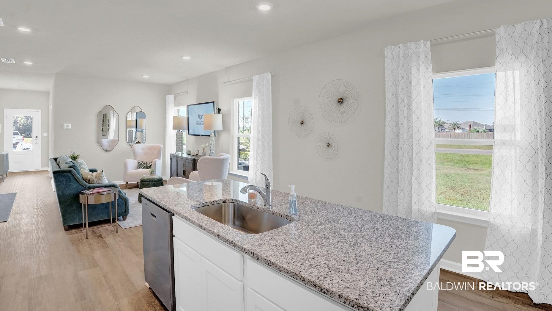 13330 Shea Circle Foley, AL 36535 - Photo 9 of 15 Open-concept living space featuring a kitchen island with built-in sink, granite countertops, wood-finish flooring, recessed lighting, and bright windows