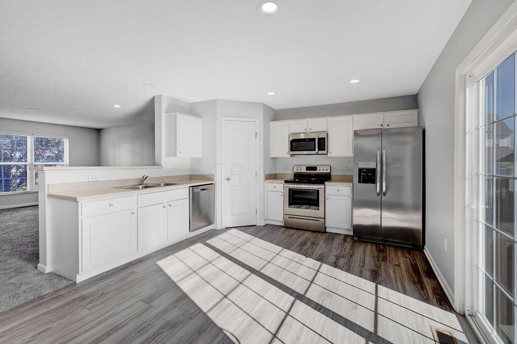 6345 Needletail Road, Unit 24634 Columbus, OH 43230 - Photo 9 of 58 • New luxury vinyl plank flooring ~ 2021 • Gray painted walls • Bevelled edge countertops • White, raised panel cabinets • Double bowl, stainless steel sink • New Frigidaire® dishwasher ~ 2021 • New Frigidaire® electric range ~ 2021 • New Frigidaire® microwave ~ 2021 • New Frigidaire® refrigerator ~ 2021 • Step-in pantry closet • Can lighting • Insinkerator® disposal • New double sliding doors (2020) to privacy fenced, paver patio