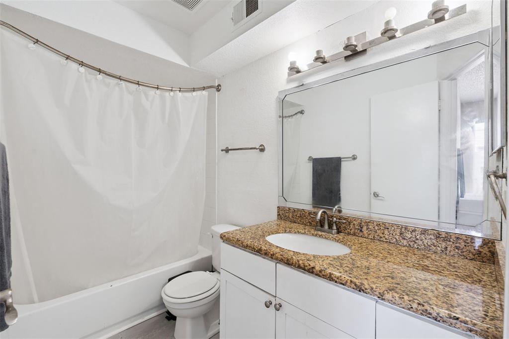 5120 Conroy Road, Unit 28 Orlando, FL 32811 - Photo 16 of 39 a bathroom with a granite countertop sink a toilet and a mirror