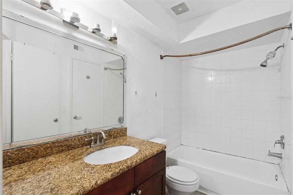 5120 Conroy Road, Unit 28 Orlando, FL 32811 - Photo 17 of 39 a bathroom with a granite countertop sink toilet a mirror and shower