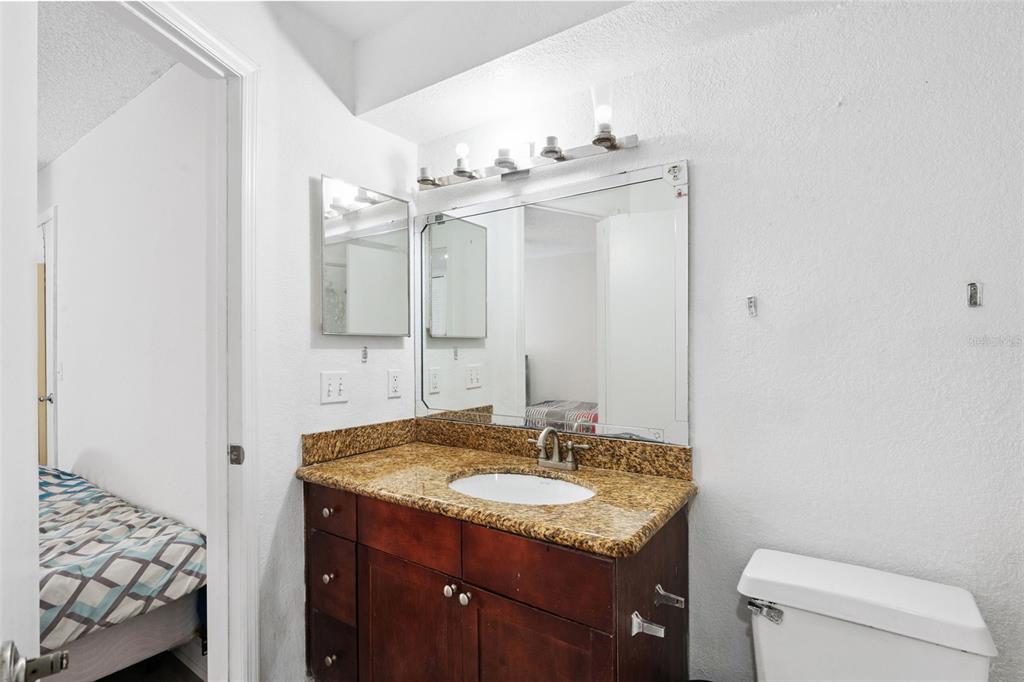 5120 Conroy Road, Unit 28 Orlando, FL 32811 - Photo 18 of 39 a bathroom with a granite countertop sink a toilet and a mirror
