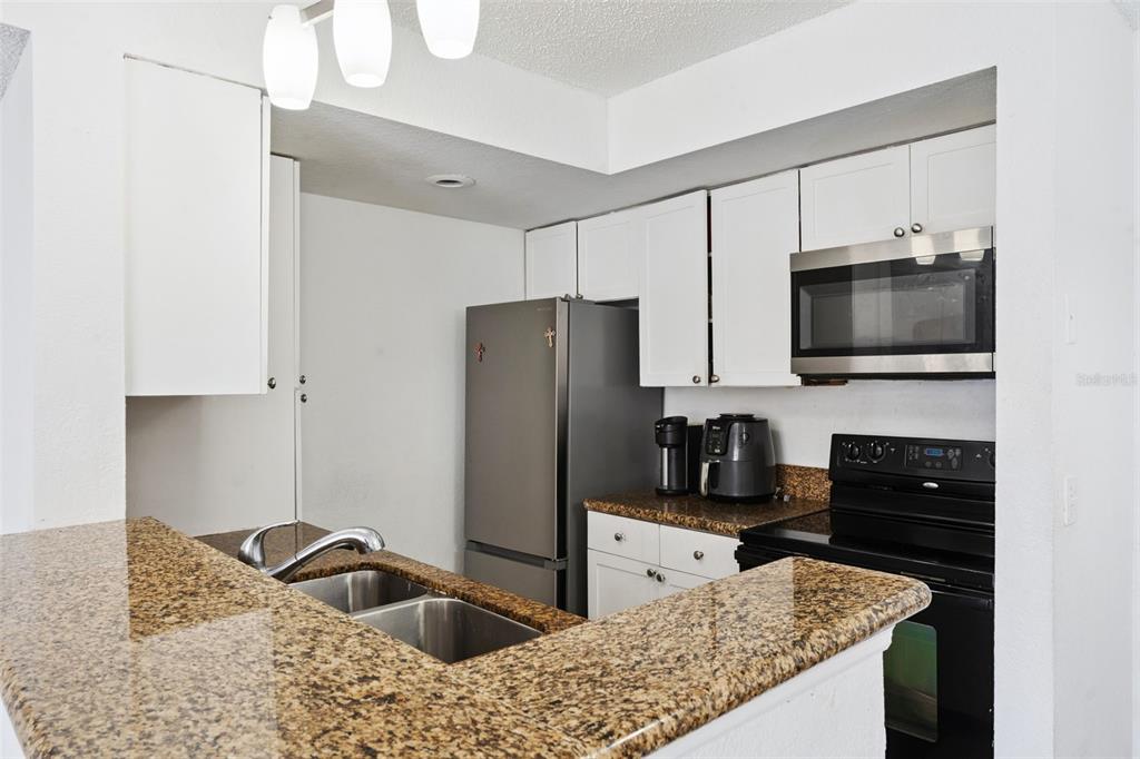 5120 Conroy Road, Unit 28 Orlando, FL 32811 - Photo 10 of 39 a kitchen with granite countertop a refrigerator and a sink