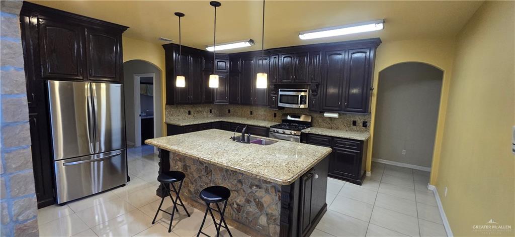 5312 Mile 4 Road Mission, TX 78573 - Photo 6 of 13 Kitchen featuring arched walkways, appliances with stainless steel finishes, light tile patterned floors, and decorative light fixtures