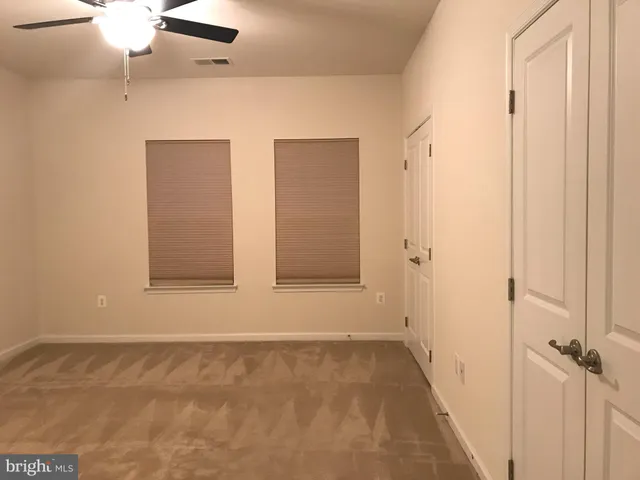 an empty room with a ceiling fan and a window