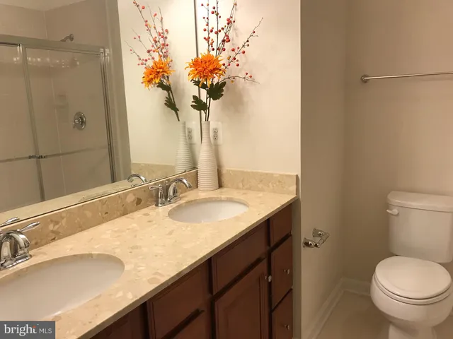 a bathroom with a granite countertop sink a toilet and a mirror