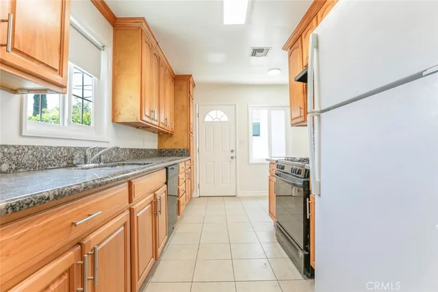 a large white kitchen with granite countertop a sink and dishwasher a stove with wooden floor