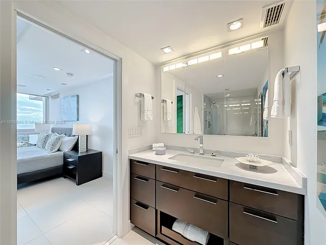 a bathroom with a granite countertop sink a large mirror and a shower