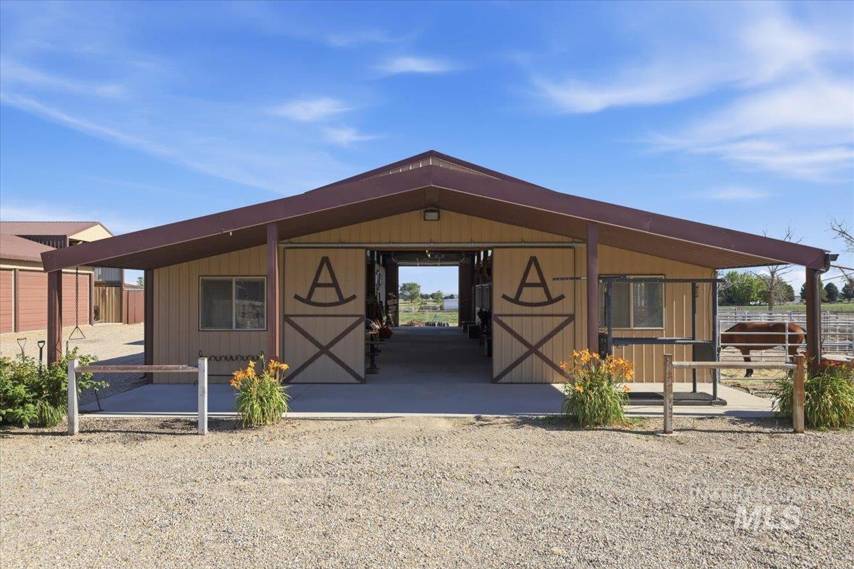 20337 Maggard Lane Caldwell, ID 83607 - Photo 31 of 50 Tack room, vet/grooming area and storage areas are on left side and 6 lighted stalls with individual electrical outlets to the right. Ceiling fans are all above the aisle. Saddle racks fold down in front of each stall.