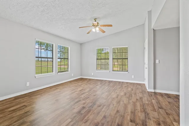a view of empty room with wooden floor and fan