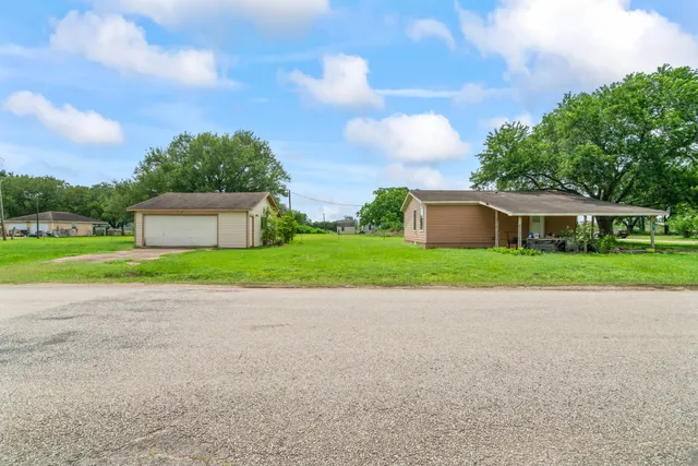 a view of a house with a yard and large tree
