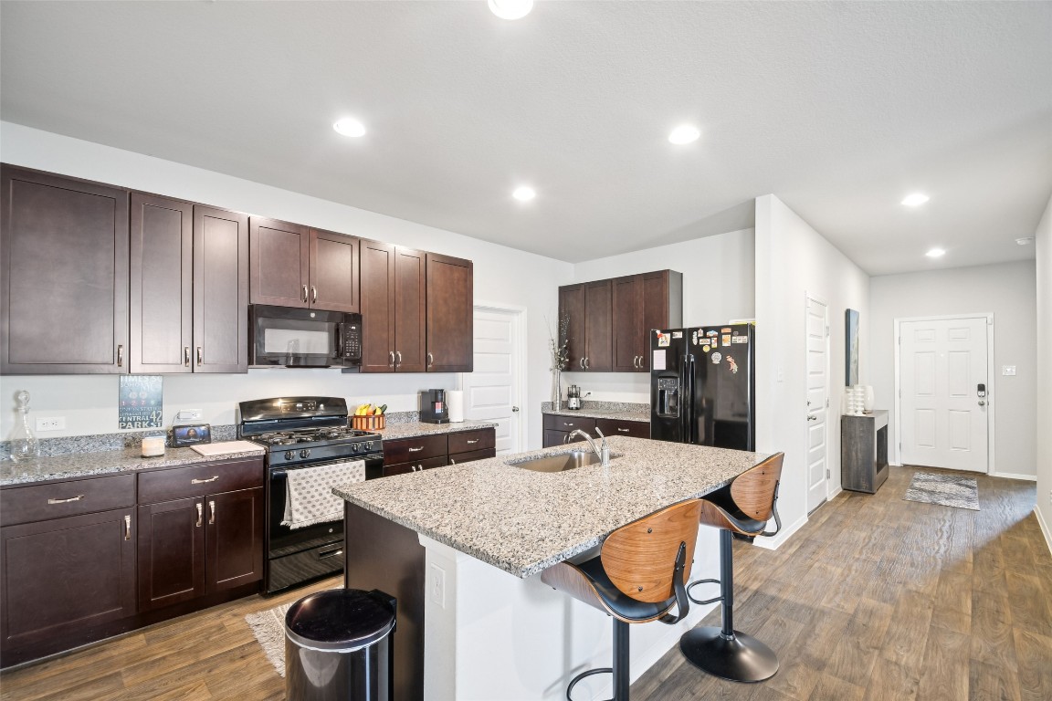5525 Sacra Cove Austin, TX 78747 - Photo 5 of 20 a kitchen with stainless steel appliances granite countertop a stove top oven a sink dishwasher and a refrigerator with wooden floor