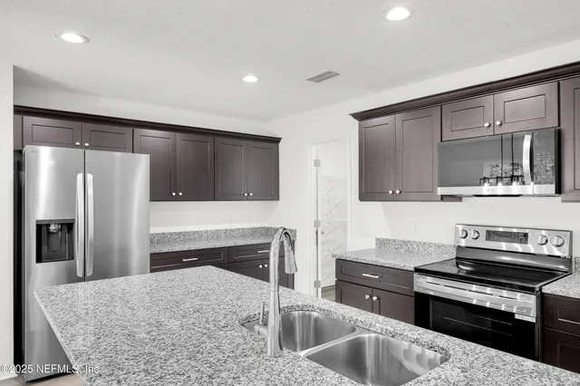 a kitchen with stainless steel appliances granite countertop a refrigerator and a stove top oven