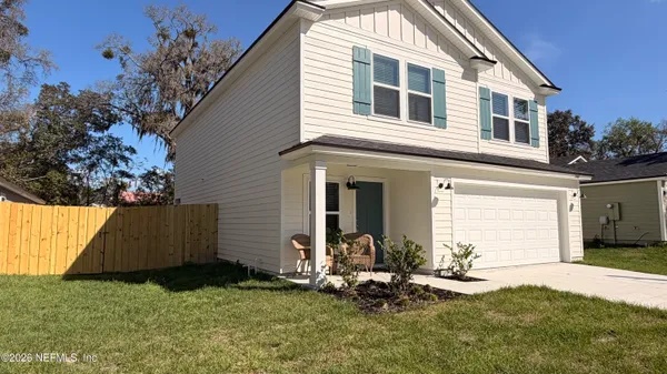 a backyard of a house with wooden fence and a tree