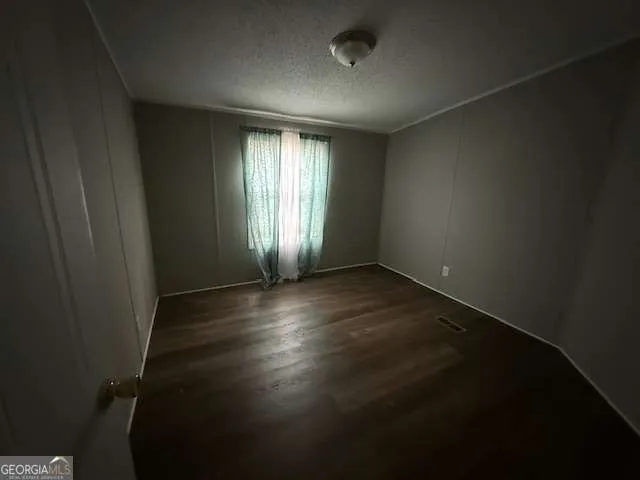 an empty room with wooden floor and windows with curtains