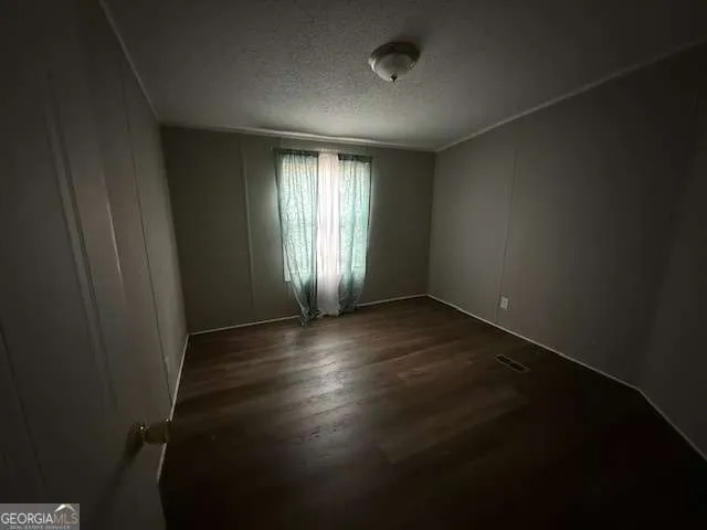 an empty room with wooden floor and windows with curtains