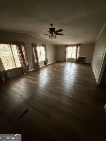 an empty room with wooden floor chandelier and windows