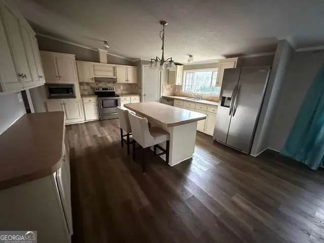 a kitchen with stainless steel appliances kitchen island granite countertop a refrigerator a stove a sink and a microwave with wooden floor