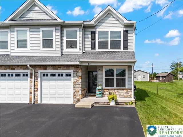 a front view of a house with a yard and potted plants