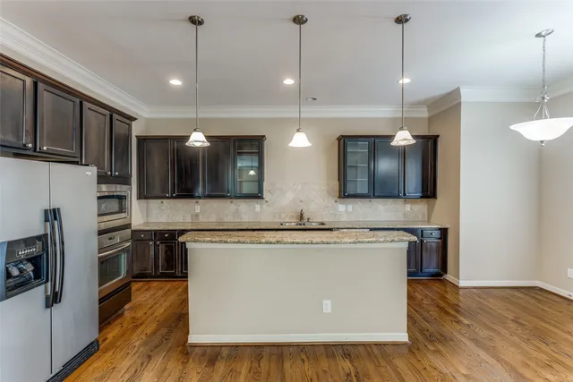 a view of a kitchen with stainless steel appliances granite countertop wooden floors and granite counter tops