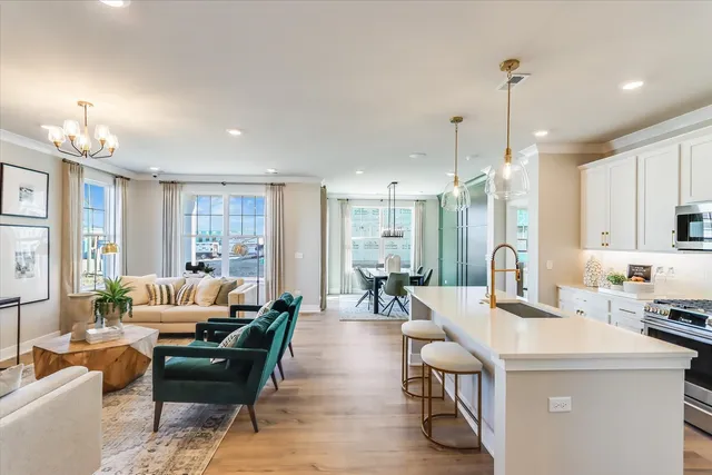 a living room with furniture kitchen area and a chandelier