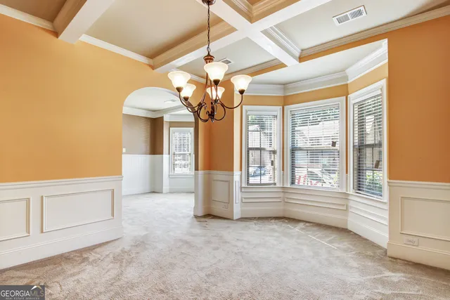 an empty room with chandelier fan and windows