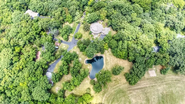 an aerial view of a house with outdoor space and trees all around