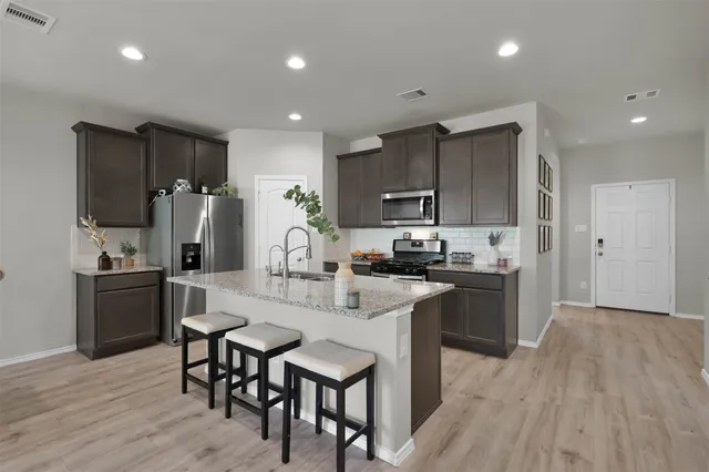 a kitchen with refrigerator a sink and chairs