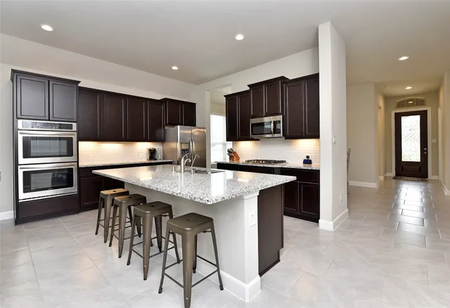 a kitchen with kitchen island granite countertop wooden cabinets a refrigerator and a stove