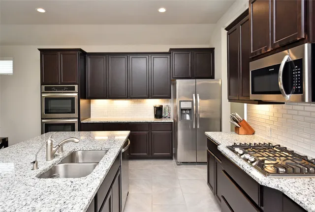 a kitchen with granite countertop a refrigerator stove and oven