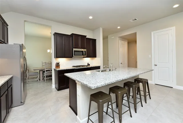 a kitchen with stainless steel appliances granite countertop table chairs sink refrigerator and microwave